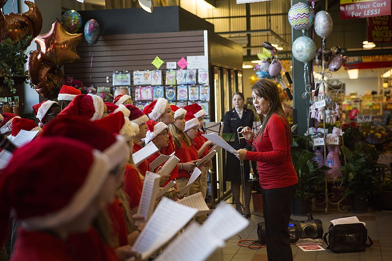 Leann Meyer directs the sixth-grade choir from Lewis and Clark Middle School while they perform Christmas carols Friday morning, Nov. 7, 2014 at Schnucks during the Salvation Army Kettle Campaign kickoff party. 