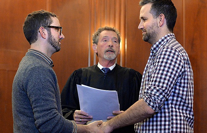 Vernon Scoville, officiates during Robert Gann, left, and John Kenny Rodricks, right, wedding at the Jackson County Courthouse Legislative Chambers, Friday, Nov. 7, 2014, in Kansas City, Mo. Scoville is retired associate circuit judge for Jackson County. Same-sex marriages began occurring Friday in the Kansas City area after a federal judge declared that Missouri's ban on gay marriage violates the U.S. Constitution.