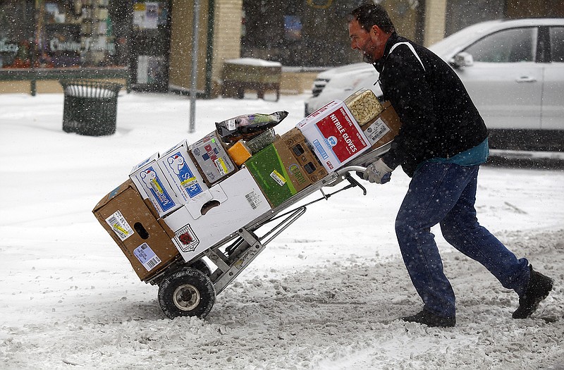 Paul Nettles pushes his cart through the snow while delivering food to restaurants Monday morning in downtown Rapid City, S.D. Wet snow accumulating to as much as 6 inches, strong winds and cold temperatures made for a tough day across the Black Hills.