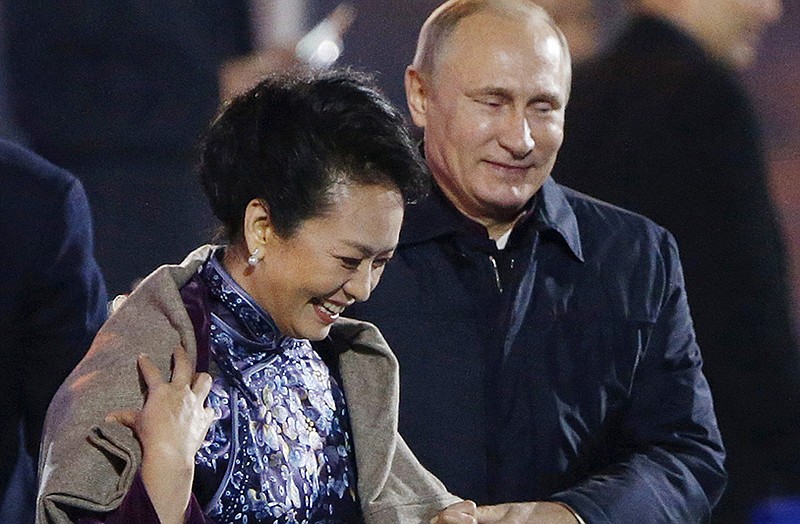 Russia's President Vladimir Putin, right, puts a shawl on Peng Liyuan, left, wife of Chinese President Xi Jinping.
