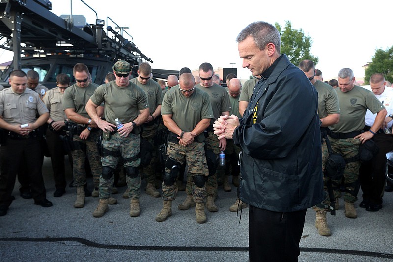 In this Aug. 18 photo, Rev. Michael Boehm says a prayer during roll call with police officers and St. Louis County Police tactical team as they make a plan for how to deal with crowds of people along W. Florissant Road in Ferguson, Mo. The unrest in Ferguson over the past three months has led many police officers to seek counsel with chaplains, who say frustrated officers welcome the opportunity to vent. The Aug. 9 fatal shooting of Michael Brown by Ferguson police officer Darren Wilson has caused residents and others to protest in St. Louis County. A grand jury is considering whether Wilson should be charged.