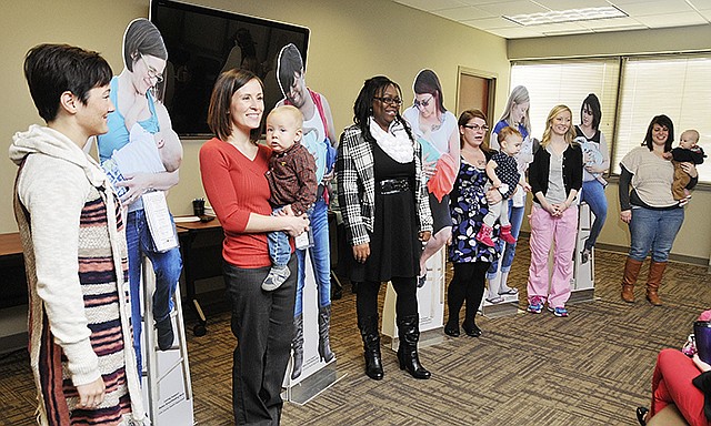 Photographer Janelle Harris, left, stands next to the life-sized standup photograph of Misty Prenger breastfeeding her son, Tristan. Standing next to the cutout is Prenger and Tristan, along with other models, Racquel Hykes, Kristi Berney and Abagail, Jaimi and at far right, is Brittanie Schaben holding her son, Elijah.