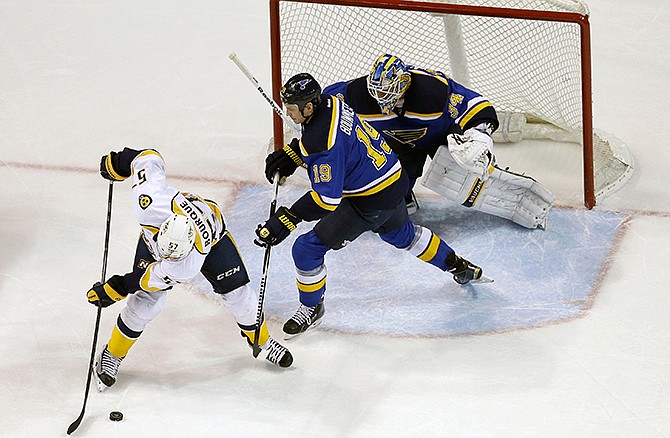 Nashville Predators' Gabriel Bourque, left, tries to control the puck as St. Louis Blues goalie Jake Allen and Jay Bouwmeester (19) defend during the second period of an NHL hockey game Thursday, Nov. 13, 2014, in St. Louis.