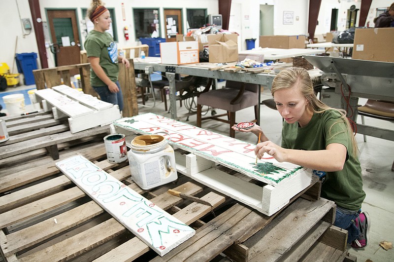 Emily Hampton, a University of Missouri sophomore, paints wood pallets Saturday inside Kingdom Projects Inc. as a service project. Hampton and 11 other MU students who volunteered at KPI this weekend are members of the university's Mizzou Alternative Break program in which students forgo a break - Thanksgiving, semester, etc. - to participate in a volunteer activity. Students decorated the wood pallets which will be sold to benefit KPI. The painted pallets will be used as examples for employees when KPI rolls out its own pallet project.