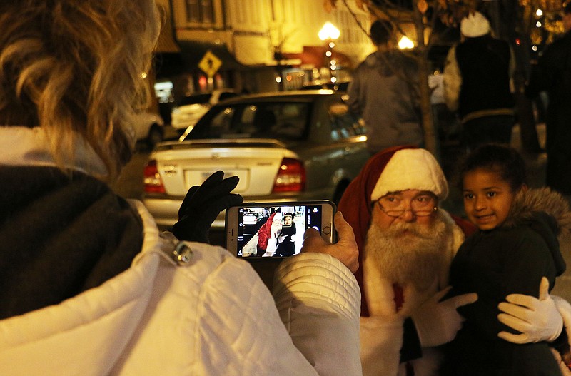 A young girl poses for a picture with Santa Clause during the holiday open house Friday night. Santa Clause walked up and down Court Street in Fulton, taking pictures with shoppers and asking children what they wanted for Christmas.