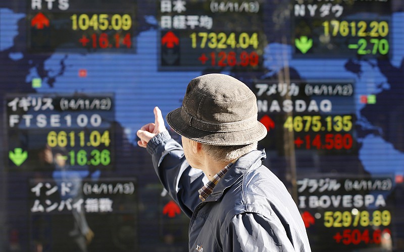 In this Nov. 13, 2014 file photo, a man looks at an electronic stock board of a securities firm in Tokyo. The Treasury Department released foreign holdings data for August on Tuesday, Nov. 18, 2014. 