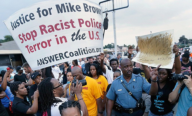 In this Aug, 16, 2014 file photo, Missouri Highway Patrol Capt. Ron Johnson walks among people protesting the police shooting death of Michael Brown in Ferguson, Mo. Missouri police have been taking a refresher course on people's constitutional rights while simultaneously stocking up on new riot gear in advance of a grand jury decision on whether to charge a white police officer who fatally shot a black 18-year-old in suburban St. Louis. 