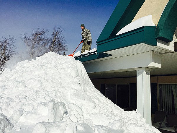 In this photo taken on Wednesday and released by the New York National Guard, an airman with the New York Air National Guard shovels snow off the roof of the Eden Heights Assisted Living Facility in West Seneca, New York.