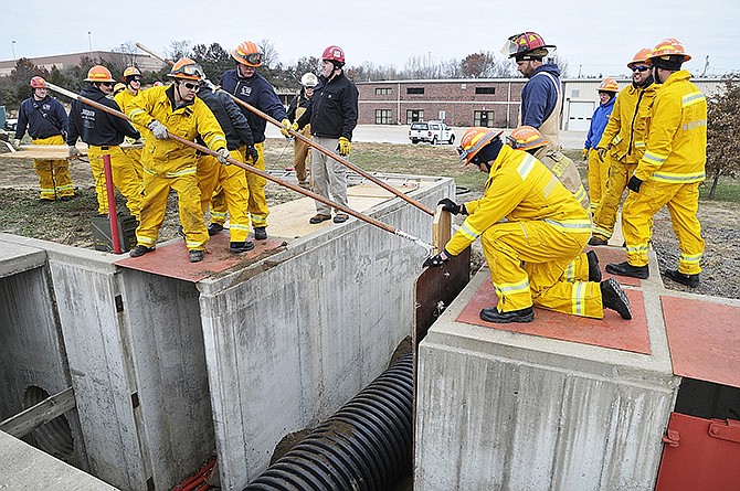 Firefighters slide a shoring panel down the wall and into place during training at Hyde Park Friday. Several members of the Jefferson City Fire Department participated the trench collapse training thanks to a FEMA grant the department received earlier this year.