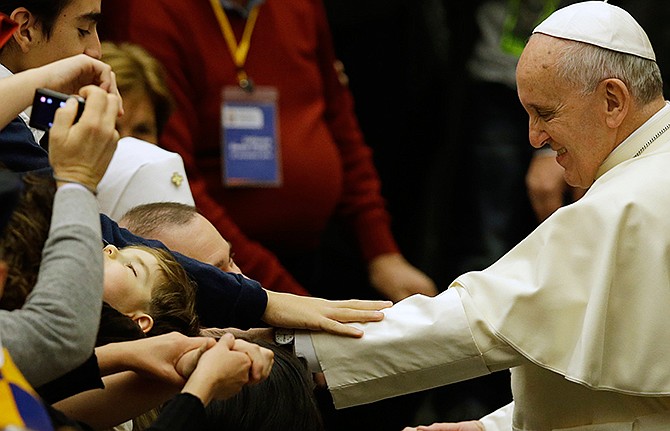 Pope Francis greets faithful during an audience with health care workers and children with autism in the Paul VI hall at the Vatican, Saturday, Nov. 22, 2014. 