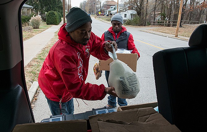 Jay Campbell, left, a masters student at Lincoln University, and Christian Thompson, president of Kappa Alpha Psi, unload their last Thanksgiving dinner delivery from the back of an SUV Saturday morning. Volunteers gathered at the Elks Lodge in Jefferson City before delivering Thanksgiving dinners to various families around the city.