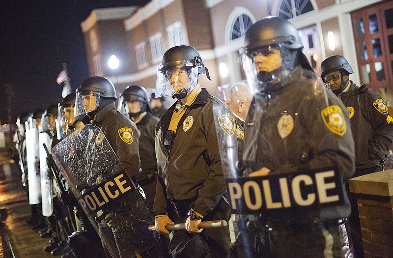 Police stand guard during a demonstration outside the Ferguson Police Department, Sunday. Ferguson and the St. Louis region are on edge in anticipation of the announcement by a grand jury whether to criminally charge Officer Darren Wilson in the killing of 18-year-old Michael Brown. 