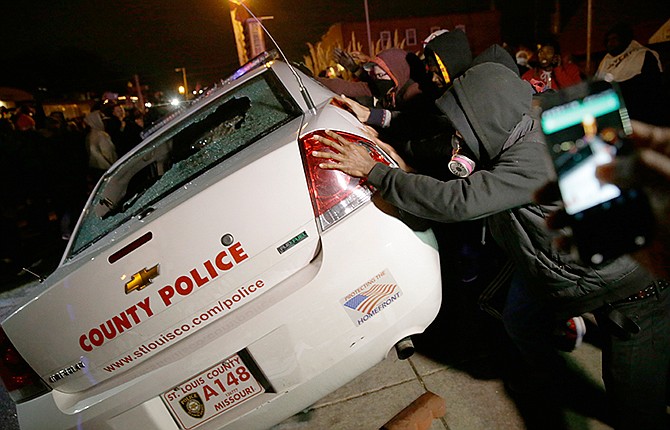 A group of protesters vandalize a police vehicle after the announcement of the grand jury decision not to indict police officer Darren Wilson in the fatal shooting of Michael Brown, an unarmed black 18-year-old, Monday, Nov. 24, 2014, in Ferguson, Mo.