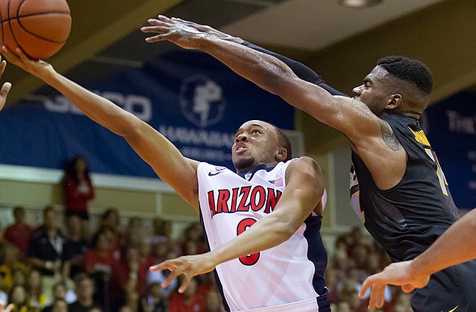 Arizona guard Parker Jackson-Cartwright, left, ducks under Missouri guard Keith Shamburger, right, and shoots a layup in the first half of an NCAA college basketball game at the Maui Invitational on Monday, Nov. 24, 2014, in Lahaina, Hawaii.