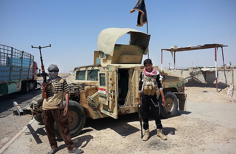 Islamic State group militants stand by a captured Iraqi army Humvee at a checkpoint in Iraq.
