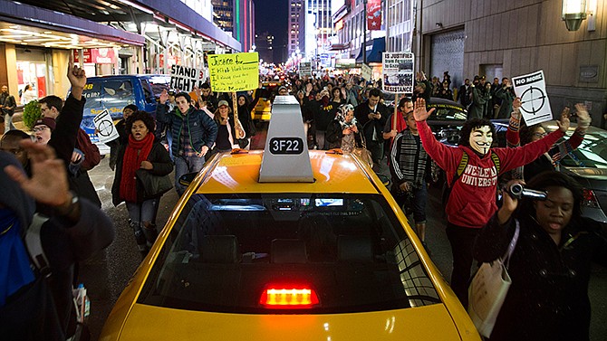 Demonstrators march with their hands raised in protest against a grand jury's decision on Monday not to indict Ferguson police officer Darren Wilson in the fatal shooting of Michael Brown, Tuesday, Nov. 25, 2014, in New York. The grand jury's decision has inflamed racial tensions across the U.S. 