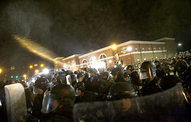 Police shoot pepper spray toward protesters in front of the Ferguson Police Department on Tuesday, Nov. 25, 2014, in Ferguson, Mo. Missouri's governor ordered hundreds more state militia into Ferguson on Tuesday, after a night of protests and rioting over a grand jury's decision not to indict police officer Darren Wilson in the fatal shooting of Michael Brown, a case that has inflamed racial tensions in the U.S.