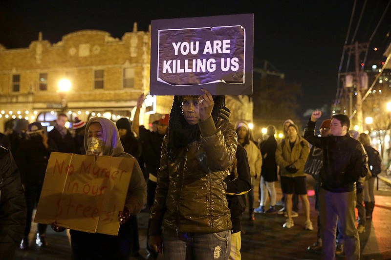 Protesters hold up signs as they gather Tuesday, Nov. 25, 2014, in St. Louis. Missouri's governor ordered hundreds more state militia into Ferguson on Tuesday, after a night of protests and rioting over a grand jury's decision not to indict police officer Darren Wilson in the fatal shooting of Michael Brown, a case that has inflamed racial tensions in the U.S.