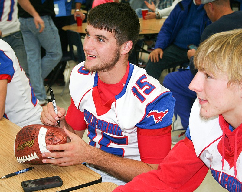 California senior Jaden Barr (left) signs a football for one of his fans while teammate Allan Burger looks on. Barr and Burger each signed plenty of autographs at the Pintos' meet-and-greet with community members on Thursday, Nov. 20.