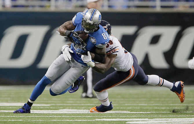 Detroit Lions wide receiver Calvin Johnson (81) is tackled by Chicago Bears inside linebacker Christian Jones (59) after his 9-yard reception during the first half of an NFL football game in Detroit, Thursday, Nov. 27, 2014. With this catch, Johnson set a new NFL record for fewest games (115) to reach 10,000 career receiving yards. 