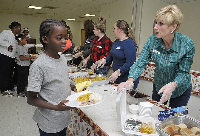 Lisa Oetting, right, serves 10 year-old Jahair Easton who commented that he hadn't seen so much food in one place as he made his way through the serving line. He was visiting his grandmother at Dulle and Hamilton Towers and was able to enjoy the meal served by volunteers. Several members of Immaculate Conception Parish have made it a practice to serve others on Thanksgiving Day. Volunteers do not only come from the church but outside of it as well to help out with the meal of turkey, dressing and the fixings.