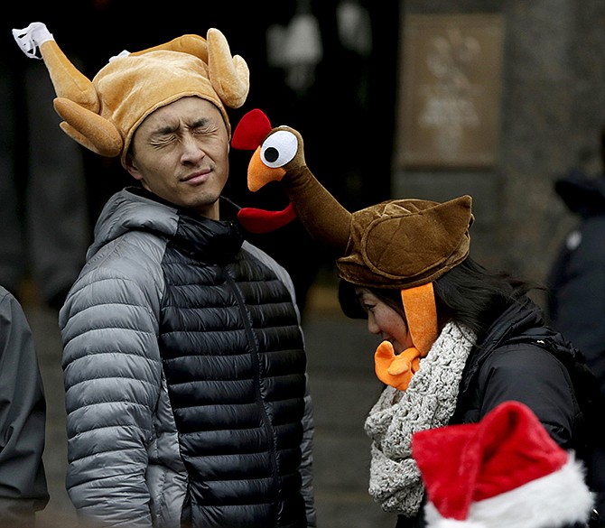 Tamari Hedani, right, hits her boyfriend, Chris Chu, both from San Francisco, with her turkey hat prior to the start of the Macy's Thanksgiving Day Parade, Thursday.
