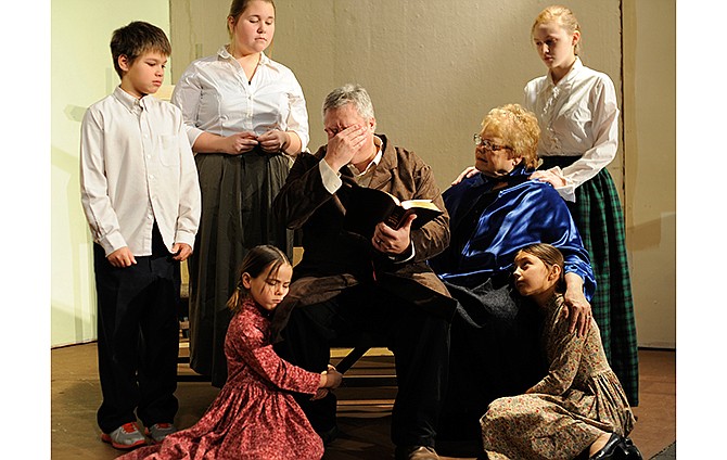 Bob Cratchit, center, played by Rob Hargis, wipes his eyes after reading a passage from the Bible as he and his family mourn the loss of their son Tiny Tim as part of his boss Ebenezer Scrooge's vision of Christmas future during a dress rehearsal for Stained Glass Theatre's upcoming production of the beloved Charles Dickens holiday
classic, "A Christmas Carol."