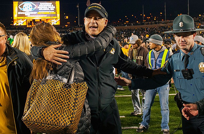 Missouri head coach Gary Pinkel, center, is hugged by fans after they defeated Arkansas 21-14 in an NCAA college football game Friday, Nov. 28, 2014, in Columbia, Mo.