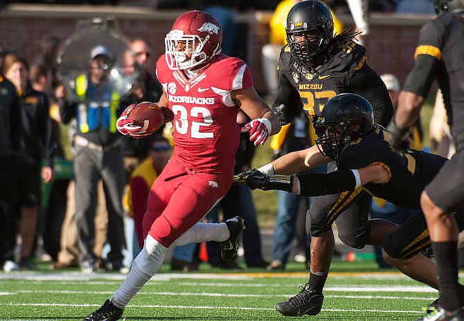 Arkansas running back Jonathan Williams, left, runs past Missouri's Markus Golden, top right, and Michael Scherer during the second quarter of an NCAA college football game Friday, Nov. 28, 2014, in Columbia, Mo. 