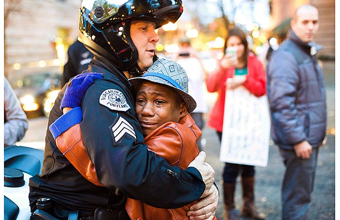 In this Tuesday, Nov. 25, 2014 photo provided by Johnny Nguyen, Portland police Sgt. Bret Barnum, left, and Devonte Hart, 12, hug at a rally in Portland, Ore., where people had gathered in support of the protests in Ferguson, Mo.