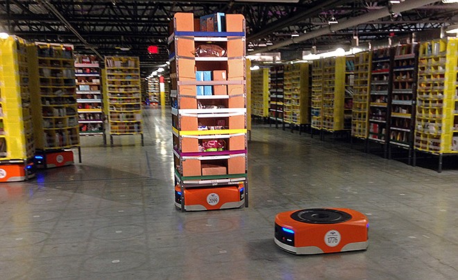 A Kiva robot drive unit is seen, foreground, before it moves under a stack of merchandise pods, seen on a tour of one of Amazon's newest distribution centers in Tracy, California, Sunday. This Amazon Fulfillment Center opened in 2013 and was refitted to use new robot technology this summer.