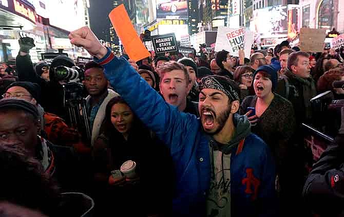 Protestors shout at Times Square after it was announced that the New York City police officer involved in the death of Eric Garner is not being indicted, Wednesday, Dec. 3, 2014, in New York. A grand jury cleared the white New York City police officer Wednesday in the videotaped chokehold death of Garner, an unarmed black man, who had been stopped on suspicion of selling loose, untaxed cigarettes, a lawyer for the victim's family said. A video shot by an onlooker and widely viewed on the Internet showed the 43-year-old Garner telling a group of police officers to leave him alone as they tried to arrest him. The city medical examiner ruled Garner's death a homicide and found that a chokehold contributed to it. 