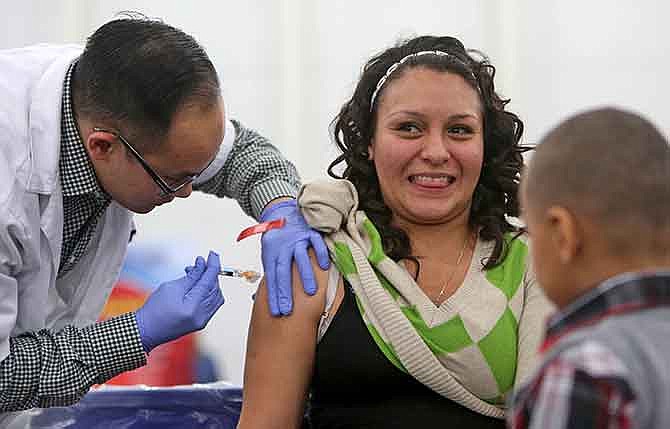 In this Nov. 27, 2014 photo, pharmacist Chris Nguyen gives a flu shot to Sandra Bazaldua in Houston, Texas. The flu vaccine may not be very effective this winter, according to U.S. health officials who worry this may lead to more serious illnesses and deaths. The Centers for Disease Control and Prevention issued an advisory to doctors about the situation Wednesday, Dec. 3, 2014.