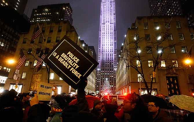 Protesters rallying against a grand jury's decision not to indict the police officer involved in the death of Eric Garner march down Fifth Avenue past the Rockefeller Center Christmas tree, Friday, Dec. 5, 2014, in New York. 
