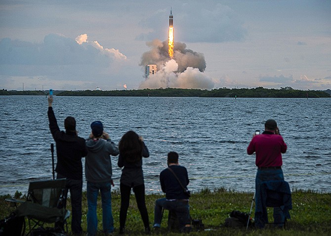 Spectators cheer as the United Launch Alliance Delta 4-Heavy rocket, with NASA's Orion spacecraft mounted atop, lifts off from the Cape Canaveral Air Force Station, Friday in Cape Canaveral, Florida.