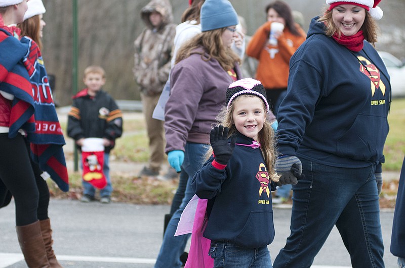 Ava Santhuff, 6, of Fulton waves while walking on Fifth Street in the 2014 Fulton Jaycees Christmas Parade on Saturday. The parade honored her twin brother - "Super" Sam Santhuff - who battled cancer for 13 months before passing away in September. The parade had a hero theme, paying tribute to emergency personnel and military as well as "Super" Sam who become a hero to many throughout his journey. Ava Santhuff walked with other "Super" Sam supporters and hand-in-hand with her mother, Cassie Santhuff.