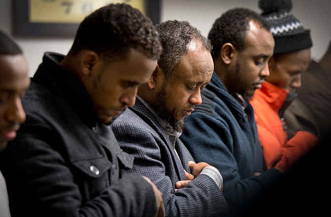 Men gather to pray the day after 15-year-old Abdisamad Sheikh-Hussein was struck and killed by a hit-and-run driver in front of the Somali Center of Kansas City, Mo., Friday, Dec. 5, 2014. An SUV driver accused of deliberately running down the Muslim teenager in Kansas City was charged Friday with first-degree murder in a case that's being investigated by federal authorities as a possible hate crime.