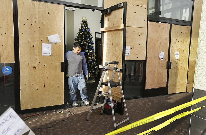 A worker pauses as he cleans up damage to Chase bank Monday, the result of a violent protest Sunday night in Berkeley, Calif. The second straight night of protests in Berkeley over police killings in Missouri and New York led to at least five arrests and left two officers with minor injuries. 