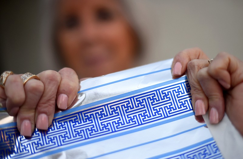 Cheryl Shapiro displays the Hanukkah gift wrap with a swastika-like pattern she found at Walgreens in Northridge, Calif., Monday. The wrapping paper has been recalled from stores nationwide. 