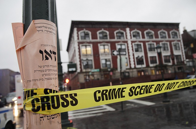 Crime scene tape is wrapped around a pole in front of Chabad-Lubavitch Hasidic headquarters, Tuesday in New York. A knife-wielding man stabbed an Israeli student inside the Brooklyn synagogue before being fatally shot by police after he refused to drop the knife. The student, Levi Rosenblatt, is in stable condition.