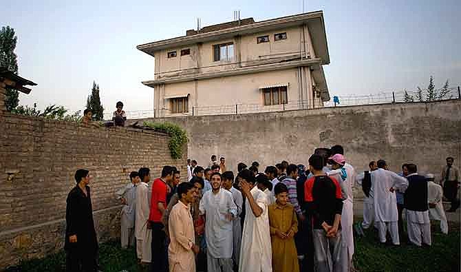 In this May 3, 2011 file photo, local residents gather outside a house, where al-Qaida leader Osama bin Laden was caught and killed in Abbottabad, Pakistan. After U.S. Navy SEALs killed Osama bin laden in Pakistan in May 2011, top CIA officials secretly told lawmakers that information gleaned from brutal interrogations played a key role in what was one of the spy agency's greatest successes. CIA director Leon Panetta repeated that assertion in public, and it found its way into a critically acclaimed movie about the operation, Zero Dark Thirty, which depicts a detainee offering up the identity of bin Laden's courier, Abu Ahmad al- Kuwaiti, after being tortured at a CIA "black site." As it turned out, Bin Laden was living in al Kuwaiti's walled family compound, so tracking the courier was the key to finding the al-Qaida leader.