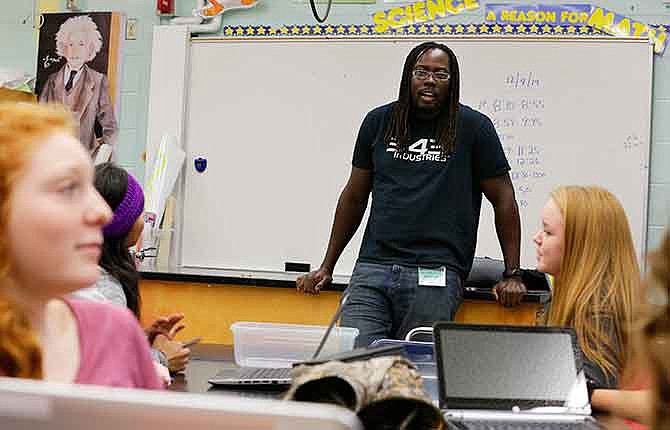 Hoop Somuah, a principal software developer with Microsoft Studios, talks to students at Pacific Middle School in Des Moines, Wash., about his job, Tuesday, Dec. 9, 2014, as part of the international Hour of Code project. The project seeks to increase interest and education in computer science by exposing students to an hour or more of simple computer programing.
