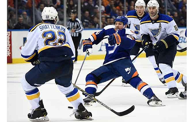 New York Islanders center Casey Cizikas (53) falls to the ice trying to control the puck against St. Louis Blues defenseman Barret Jackman (5) and defenseman Kevin Shattenkirk (22) in the second period of an NHL hockey game at Nassau Coliseum on Saturday, Dec. 6, 2014, in Uniondale, N.Y. 