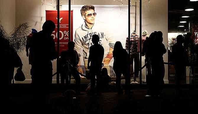 In this Nov. 28, 2013, file photo, people wait outside the American Eagle store for it to open at the Citadel Outlets in Los Angeles. Drops in sales and weak profit forecasts are quite a change for the retailers that gained popularity in the last decade among teens that coveted their logo tees and trendy jeans that became a high school uniform of sorts. But these stores have been losing favor with their core demographic since the recession. 