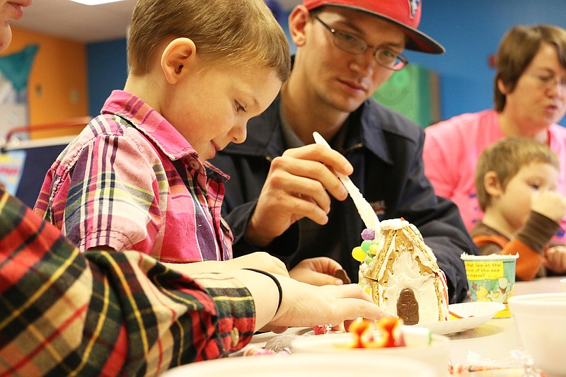 Charlie Goodman's special guests help him make a gingerbread house Thursday at Fulton Education Center. FEC students could invite special guests to school Thursday during their gingerbread house activity time.