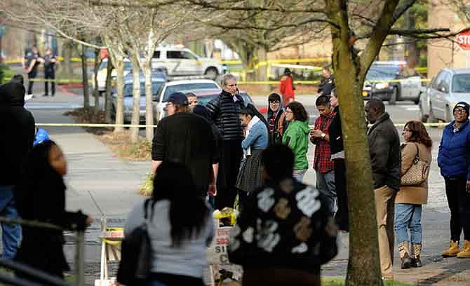 Parents and teachers gather outside Rosemary Anderson High School following a shooting at the alternative school, in Portland, Ore., Friday Dec., 12, 2014. A shooter wounded two boys and a girl outside the U.S. high school Friday in what is believed to be a gang-related attack, police said. 