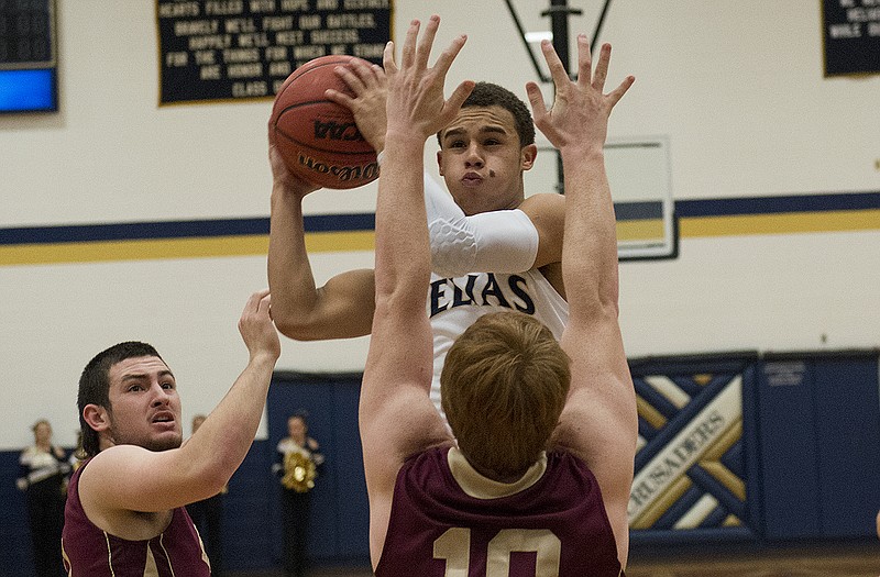 Isiah Sykes of Helias leaps into the air to take a shot as Eldon's Josh Jones puts up his arms to defend during Thursday night's game at Rackers Fieldhouse.