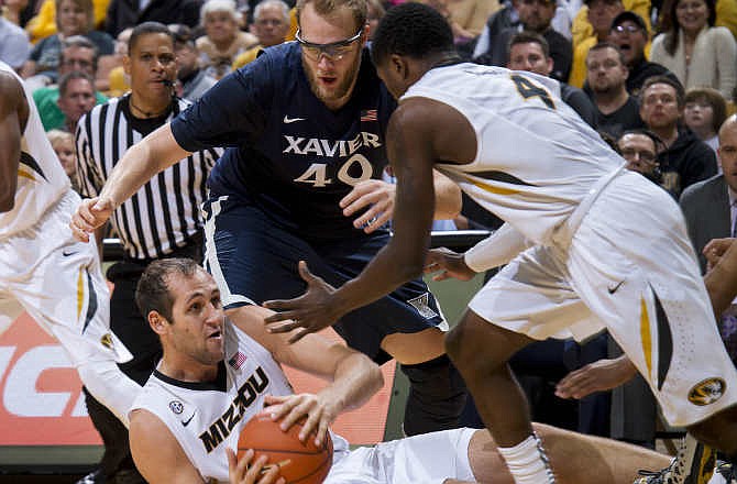 Missouri's Ryan Rosburg, bottom, looks to pass to teammate Tramaine Isabell, right, while Xavier's Matt Stainbrook tries to steal during the second half of an NCAA college basketball game Saturday, Dec. 13, 2014, in Columbia, Mo.