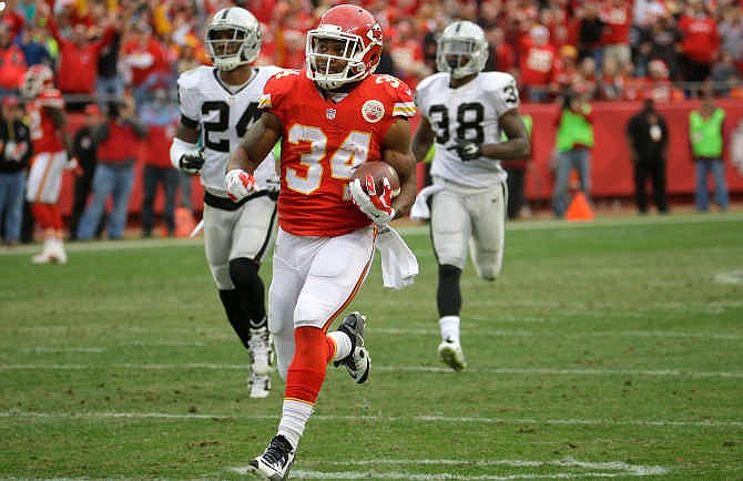 Kansas City Chiefs running back Knile Davis (34) runs for a touchdown ahead of Oakland Raiders free safety Charles Woodson (24) and cornerback T.J. Carrie (38) during the second half of an NFL football game in Kansas City, Mo., Sunday, Dec. 14, 2014. 