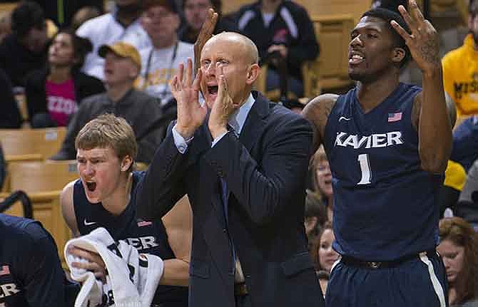 Xavier head coach Chris Mack, center, shouts instructions while Xavier players Jalen Reynolds, right, and J.P. Macura celebrate a three point shot during the first half of an NCAA college basketball game against Missouri Saturday, Dec. 13, 2014, in Columbia, Mo.